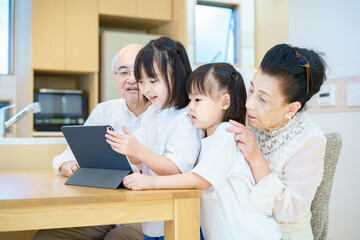 Fototapeta premium タブレットPCを操作するシニア夫婦と孫たち
