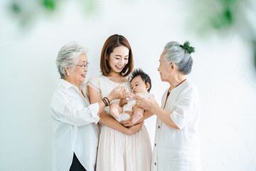 赤ちゃんを抱っこするお母さんと2人のシニア女性