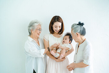 赤ちゃんを抱っこするお母さんと2人のシニア女性