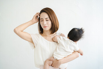 赤ちゃんを抱えて、疲れた表情をするお母さん