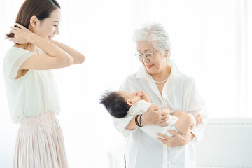 赤ちゃんを抱っこするシニア女性と見守る女性