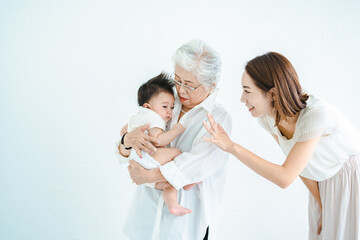 赤ちゃんを抱っこするシニア女性と見守る女性