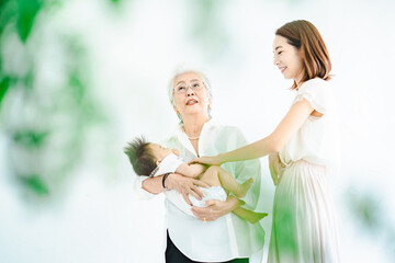 赤ちゃんを抱っこするシニア女性と見守る女性