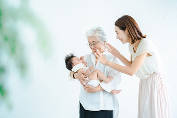 赤ちゃんを抱っこするシニア女性と見守る女性