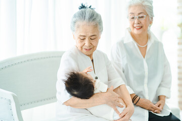 Obraz premium 赤ちゃんを抱っこするシニア女性たち