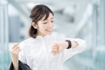 手首に着けたスマートウォッチを見る女性