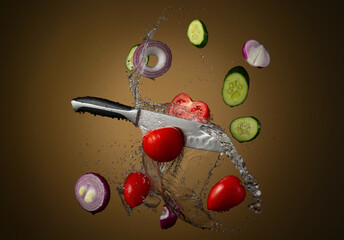 Santoku knife cutting tomato and vegetables with flying juicy splashes of water against a gradient light background. Freeze motion. High resolution.