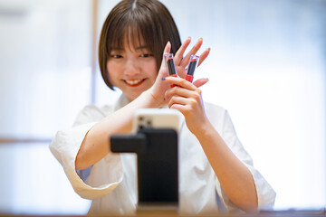 スマートフォンを使ってコスメグッズを紹介する女性