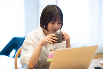 ノートPCを見ながら休憩する女性