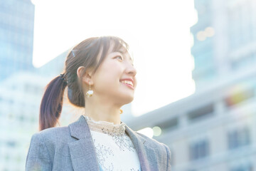 ビル街で空を見上げる若い女性