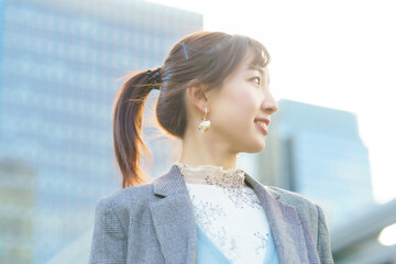 ビル街で空を見上げる若い女性