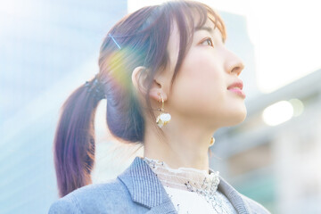 ビル街で空を見上げる若い女性