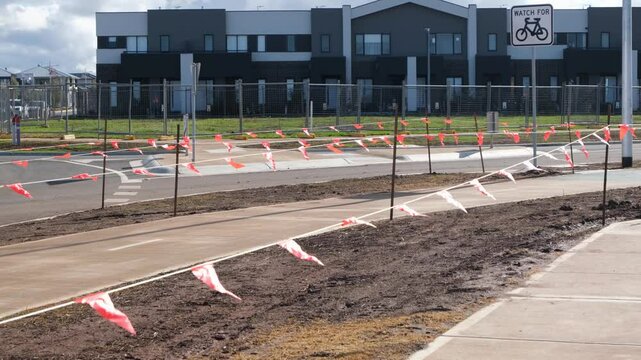 Unfinished nature strip along a newly constructed suburban footpath in an outer suburb, marked with temporary barrier. Early-stage landscaping in public space of neighborhood and urban infrastructure