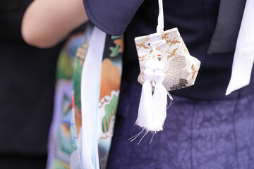In June 2025, a close-up of a protective amulet is featured during a traditional omiyamairi...