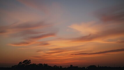 Obraz premium Magnificent sky at sunset painted in vibrant hues of orange, pink, and purple, with soft clouds drifting across the glowing horizon, creating a serene and breathtaking view of nature’s evening beauty