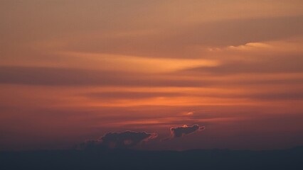 Magnificent sky at sunset painted in vibrant hues of orange, pink, and purple, with soft clouds drifting across the glowing horizon, creating a serene and breathtaking view of nature’s evening beauty
