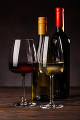 Wine glasses filled with wine beside a bottles