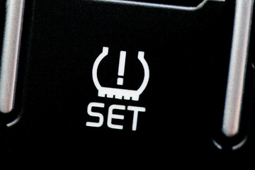 Close-up of the Tire Pressure Monitoring System (TPMS) set button in a vehicle.