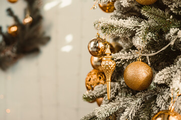 Elegant gold ornaments on a frosted Christmas tree create a warm holiday atmosphere, ideal for...