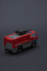 Red toy fire truck on a black background. Suitable for firefighterthemed designs, childrens educational materials, and toy store promotions.