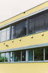 This contemporary architecture features a striking yellow building with uniquely textured walls and...