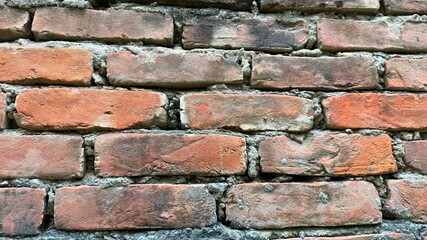 Close up displays an old orange brick wall with weathered mortar lines, showcasing texture
