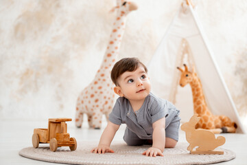 A smiling baby plays in a nursery with soft toys and a teepee, while a cute baby in a gray cotton...