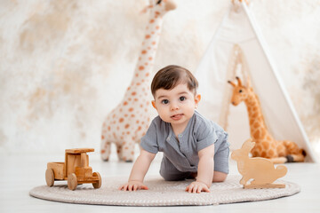 A smiling baby plays in a nursery with soft toys and a teepee, while a cute baby in a gray cotton...