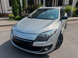 A sleek, silver compact car is parked gracefully in a lush, green environment, showcasing its...
