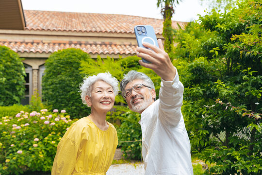 自撮り、夫婦、シニア、セルフィー、スマートフォン、スマホ、SNS、カップル、旅行、観光、笑顔、観光客、ペア、セルカタイム、動画、ピース、観光地、記念写真、高齢者、お年寄り、グレイヘア、白髪、老人、シルバー、中高年、おじいちゃん、おばあちゃん、年配、セカンドライフ、老後、熟年、60代、70代、女性、男性、日本人、ポジティブ、リラックス、元気、ハッピー、幸せ、嬉しい、庭園、新緑、楽しい、リゾート、投稿