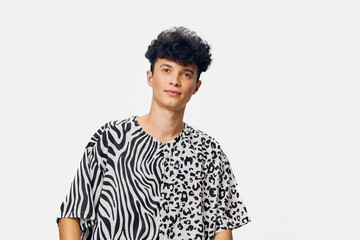 young man wearing a stylish black and white animal print t-shirt, standing against a plain white...
