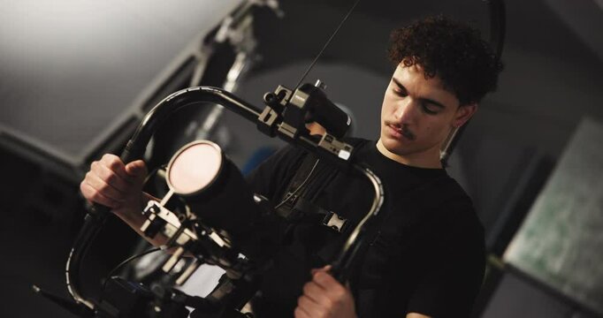 Filming, creative or cameraman with stabilizer in studio for news anchor, shooting or record. Producer, technology and people in media production with equipment or cinematographer on set for motion