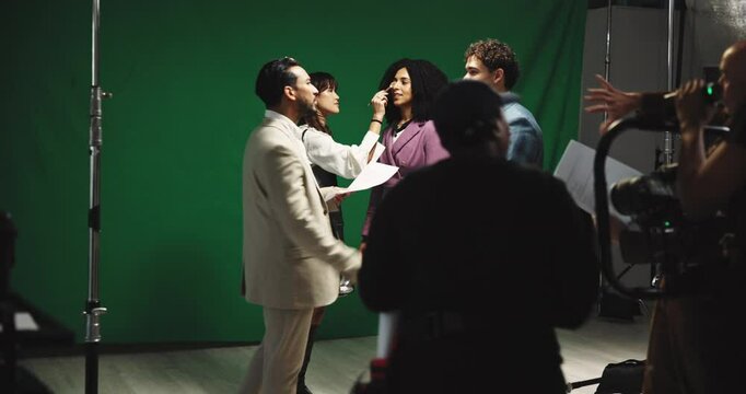 Shooting, clipboard and makeup with actress on set for filming, foundation application and broadcast. Production setup, backstage prep and reading scrip with woman in studio for process and media