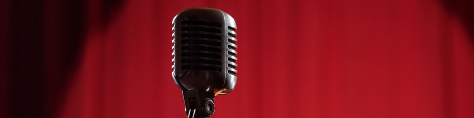 Vintage microphone standing on stage with red curtain background representing classic jazz...