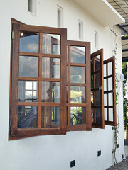 The view of the outer corner of the clean white-walled building shows dark brown wooden windows...
