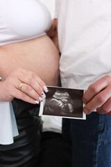 Awaiting delivery. A man and a pregnant woman hold an ultrasound image of their unborn child.
