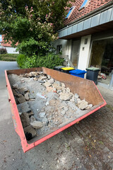 A construction debris dumpster on a busy sidewalk illustrates the challenges of cleanup, community...