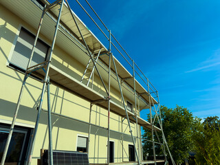 The temporary scaffolding on the large building undergoing renovation contrasts with the bright...