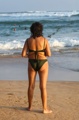 A woman in a green bikini stands on a beach