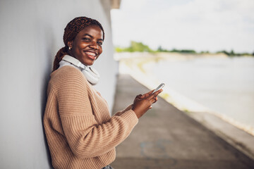 Portrait of young black woman who is messaging on smartphone.