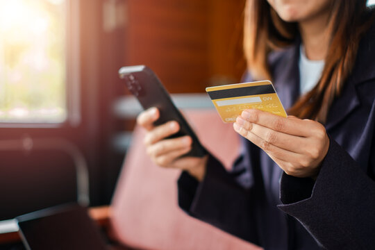 Woman using smartphone and credit card for online shopping in a cafe, highlighting digital payment and e-commerce.