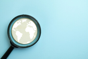 Global research concept. A magnifying glass focusing on a world map symbol on a blue background....