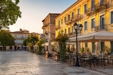 Fototapeta premium Tranquil town square with neoclassical buildings and empty cafes in nafplio, greece
