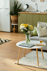 Cozy well lit interior with yellow flowers on table in modern room.
