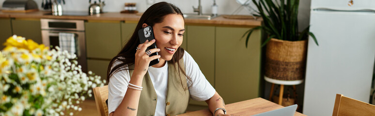 Young woman enjoys a cozy day at home while working on her laptop and chatting on the phone