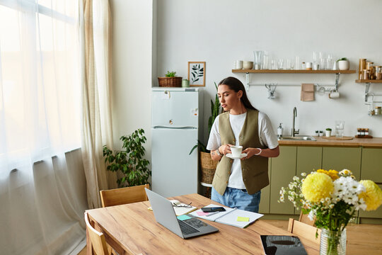 Young woman enjoying a cozy morning at home while sipping tea and working on her laptop