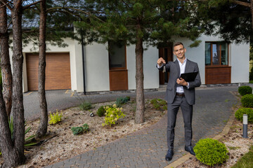 Real estate agent offering house keys and paperwork on clipboard in front of residential property
