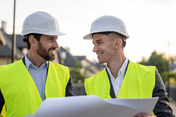 Construction team inspecting site with blueprints