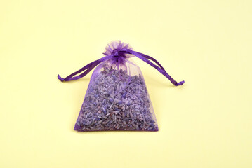 Fragrant bag filled with dried lavender flowers on the yellow background. Top view.
