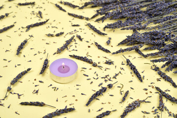 Perfumed candle and lavender flowers on the yellow background. Selective focus.
